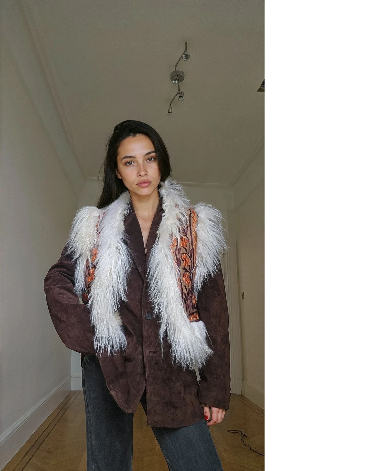 Model trägt Aql&Nafs Soraya handgefertigte Weste aus braunem Wildleder mit weißem Lammfell und floraler Stickerei.